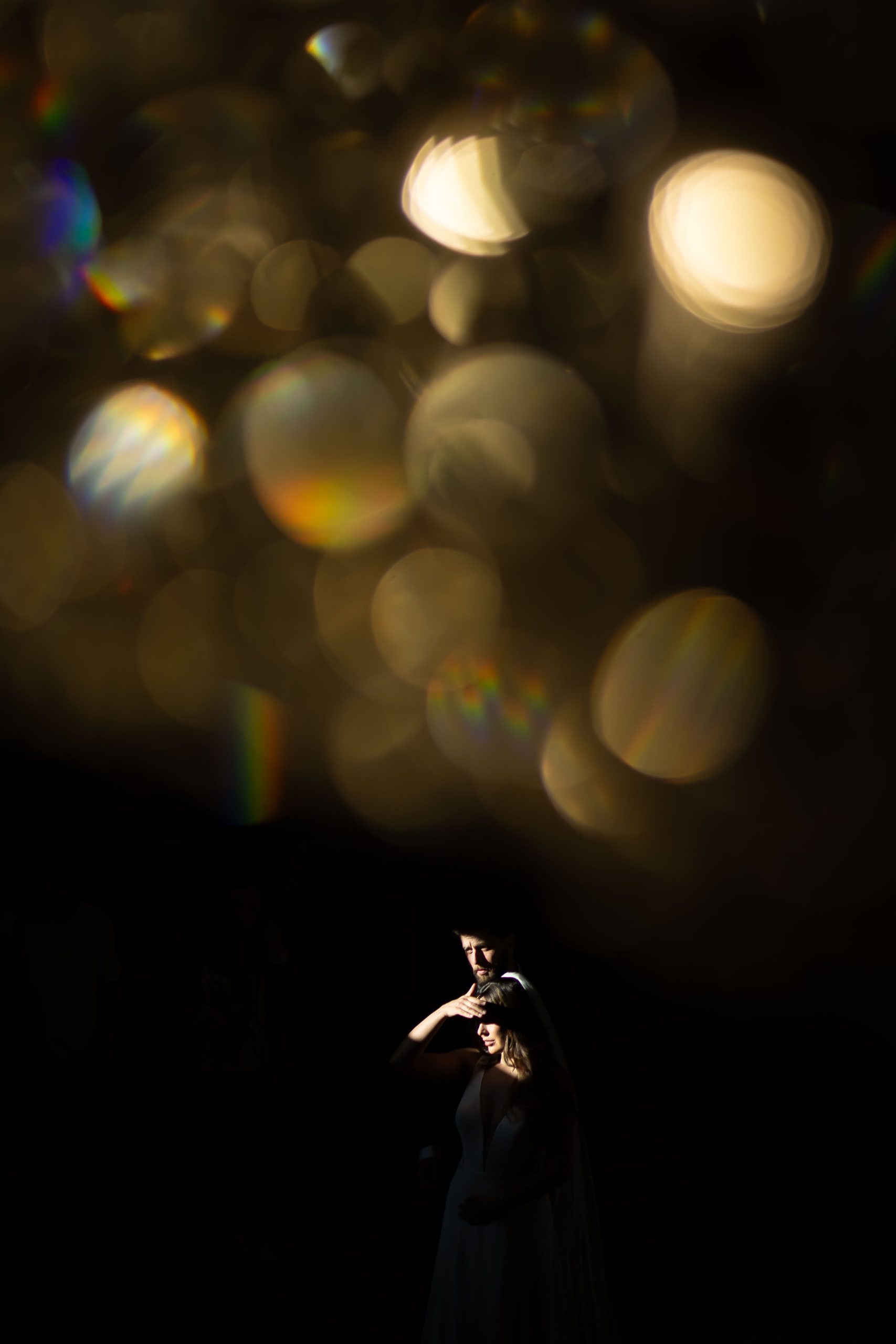 couple look out window shot through chandelier